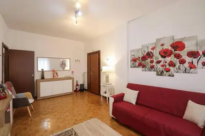 a living room with a red couch and red flowers on the wall at We Home - La Dimora di Portonaccio - Roma in Rome