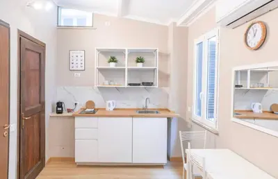 a kitchen with white cabinets and a clock on the wall at Domus Augustea - 3 Floor in Rome