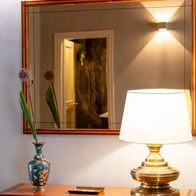 a lamp on a table with a vase and a mirror at Appartamento Roma Coronari Suite in Rome