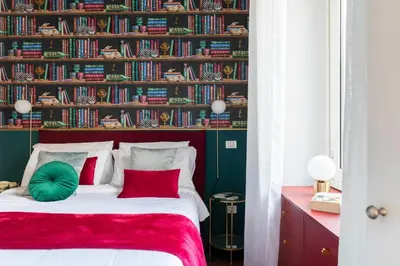 a bedroom with a bed with red and green pillows at YCH-Colosseo book house in Rome