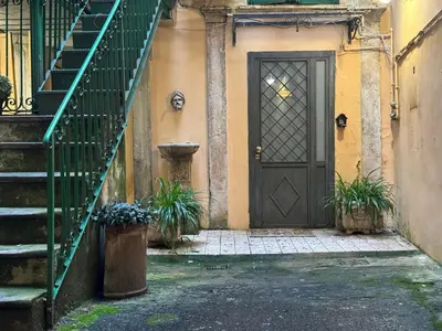 a black door in a building with stairs and plants at In Ancient Rome Apartment in Rome