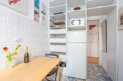 a dining room with a table and a refrigerator at Elegantis Des Artistes Apartment in Rome