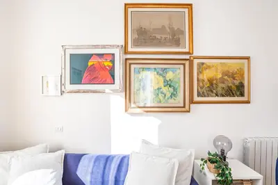 four framed paintings on a wall above a couch at Elegantis Des Artistes Apartment in Rome