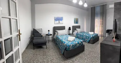 a hotel room with two beds and a chair at Giosephine House in Rome