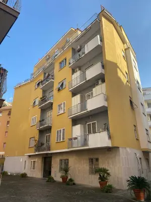 a yellow building with potted plants in front of it at Casa vacanze Belsito in Rome