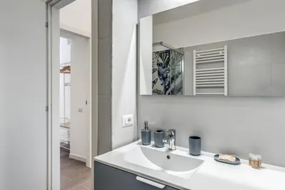 a white bathroom with a sink and a mirror at Domus Alessandro City Apartment in Rome