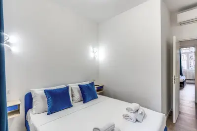 a bedroom with a white bed with blue pillows at Domus Alessandro City Apartment in Rome