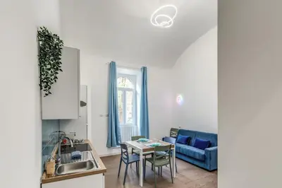 a kitchen and living room with a table and a blue couch at Domus Alessandro City Apartment in Rome