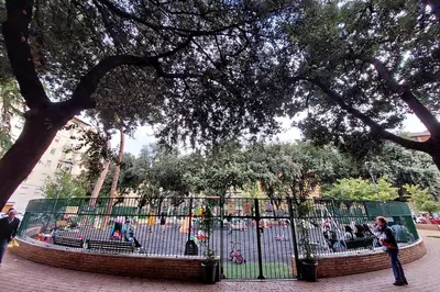 a fence in a park with people walking around at YCH-Luminoso appartamento nel cuore di Testaccio in Rome