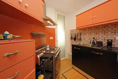 a kitchen with orange cabinets and a black stove at YCH-Riboty House al Vaticano in Rome