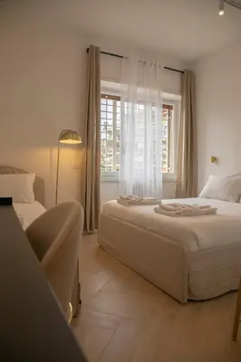 a white bedroom with two beds and a window at San Pietro Luxury Relais in Rome