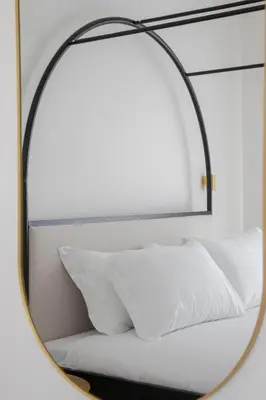 a mirror reflecting a bed with white pillows at San Pietro Luxury Relais in Rome