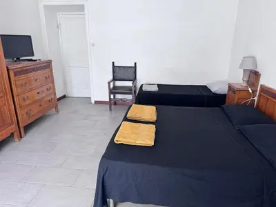 a bedroom with two beds and a tv and a chair at Martino rooms Termini in Rome