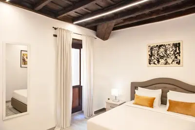 a white bedroom with a bed and a mirror at Appartamento Roma Prefetti Suite in Rome