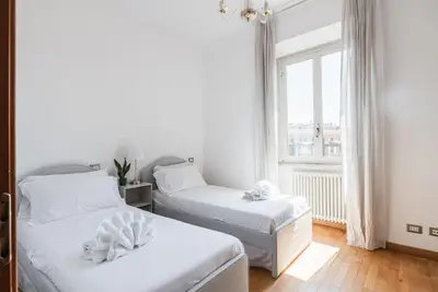 a white room with two beds and a window at Charme e Lusso a San Pietro in Rome