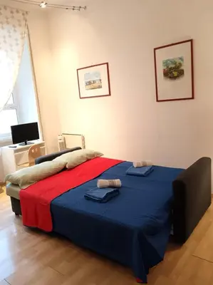 a bedroom with a bed with a blue and red blanket at san giovanni - re di roma apartment in Rome