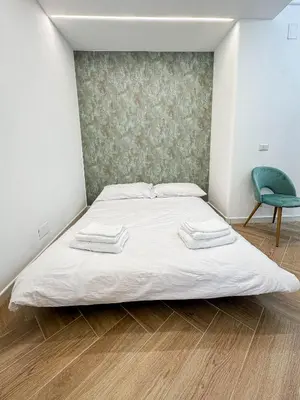 a bed in a room with a green chair at Lilla Boutique Apartment in Rome