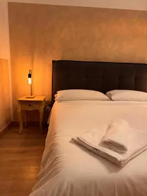 a bed with a white blanket and a lamp on a table at Unam Apartment Roma in Rome