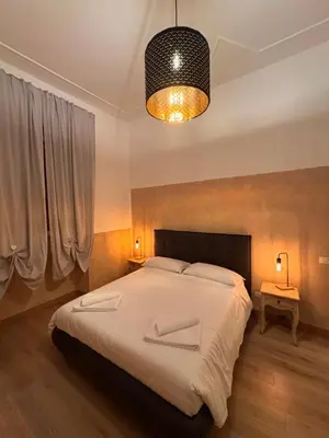 a bedroom with a large bed and a chandelier at Unam Apartment Roma in Rome