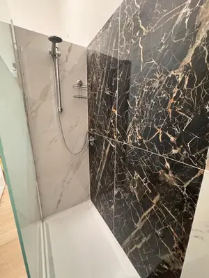 a bathroom with a shower with a black marble wall at Unam Apartment Roma in Rome