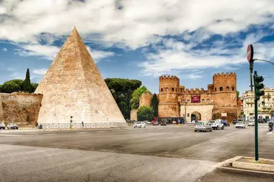 a building with a pyramid and cars parked in a street at Triple room a few steps from Tiber in Rome