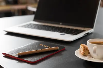 a notebook and a cup of coffee and a laptop at master Trevi in Rome