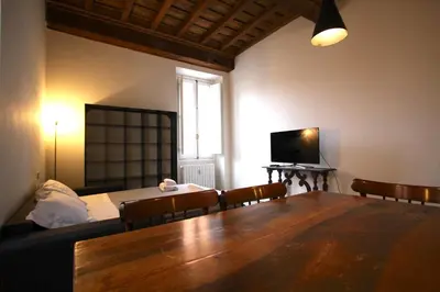 a living room with a dining room table and a television at Cartari Holiday House in Campo de Fiori in Rome