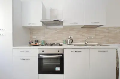 a white kitchen with a stove and a sink at White Wood House in Rome