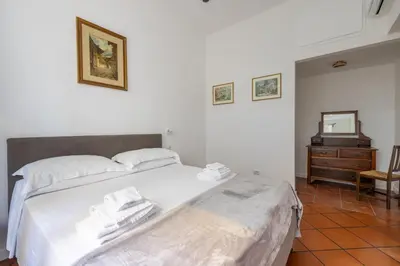 a bedroom with a large white bed and a dresser at Colosseo 85 in Rome