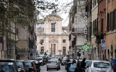 a city street with cars parked in front of a building at La Bella Vita - Trastevere in Rome