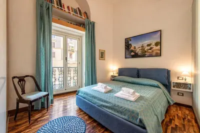 a bedroom with a blue bed and a window at Merulana Suite Apartment in Rome