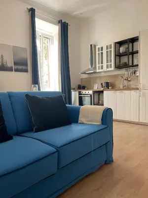 a blue couch in a living room with a kitchen at Casa Sara in Rome