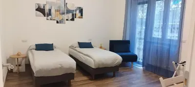 a room with two beds and a blue chair at Eve&Gio Apartment Appio 2 room 2 bath in Rome