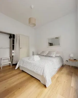 a white bedroom with a bed and a wooden floor at Vatican House big in Rome