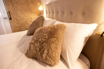 a bed with white pillows and furry pillows on it at Liu Home Tiburtina Stay in Rome in Rome