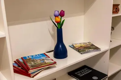 a shelf with a blue vase with flowers and magazines at Liu Home Tiburtina Stay in Rome in Rome