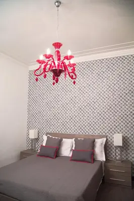 a bedroom with a large bed with a red chandelier at Nobilcasa Suites in Rome