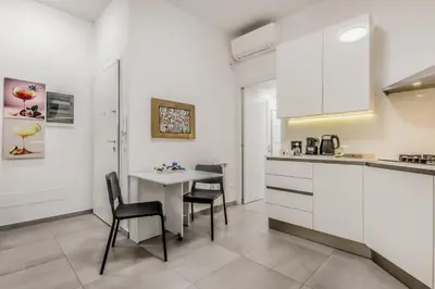 a kitchen with white cabinets and a table and chairs at White Living R-home in Rome