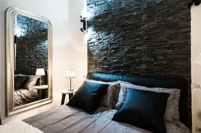 a bedroom with a brick wall and a bed with a mirror at Trevi & Pantheon Luxury Rooms in Rome