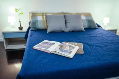 a blue bed with a book and a magazine at Marconi Suites in Rome