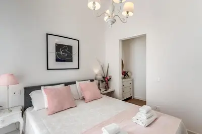 a white bedroom with a bed with pink pillows at Fresh House Vaticano in Rome