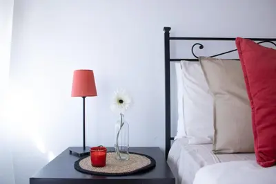 a vase with a flower on a table next to a bed at Tommys flat by DomusDimore in Rome