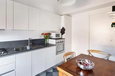a kitchen with white cabinets and a wooden table at Torretta Luxury Attico in Rome