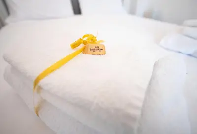 a white bed with a yellow ribbon on it at Domus Collazia - San Giovanni Apartment in Rome