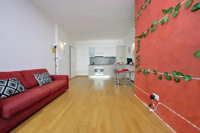 a living room with a red couch and a kitchen at Claudias flat by DomusDimore in Rome
