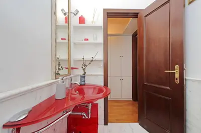 a bathroom with a red sink and a mirror at Piazza Venezia Apartment in Rome