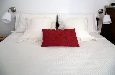 a red pillow sitting on top of a white bed at Nido Degli Angeli in Rome