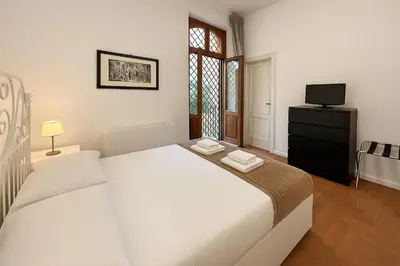 a white bedroom with a bed and a television at Femi apartments in Rome