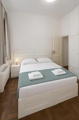 a white bedroom with a large white bed with two towels at Femi apartments in Rome