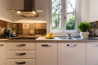 a kitchen with white cabinets and a sink and windows at Santonofrio Apartments in Rome